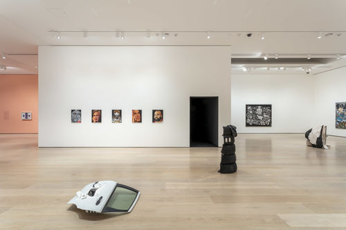 Three sculptures made of mixed objects are displayed prominently in a gallery