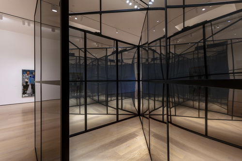 Looking inside a large, mirror-like cube with intersecting walls inside