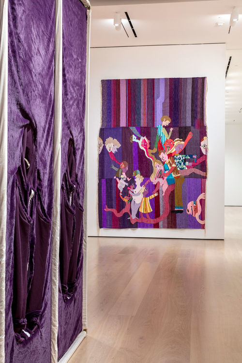 A colorful purple tapestry hanging on a gallery wall