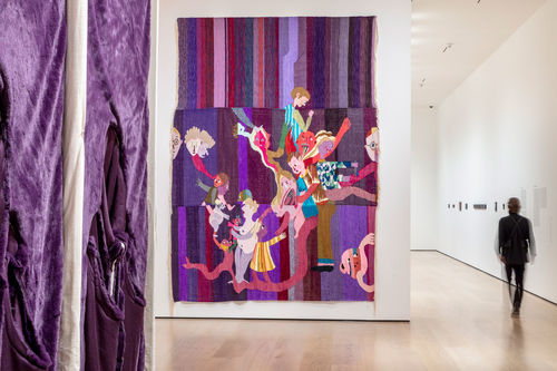A colorful purple tapestry hanging on a gallery wall