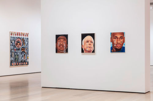A view of a gallery where several small portraits hang