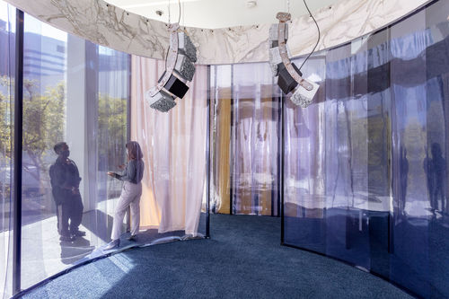 Inside an oval structure with purple plastic walls and curved speakers hanging from the ceiling