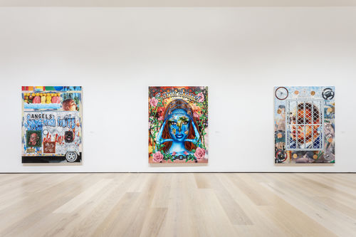 A photograph of a white-walled gallery with three colorful paintings rendered in an airbrush style synonymous with Los Angeles, low-rider car culture. The paintings are hung side-by-side with spacing between them.