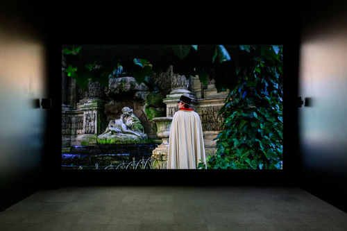 A screening room with an image of a caped man standing in a garden