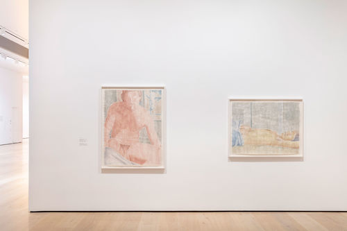 A white gallery wall with two large woodcuts of men hanging on it