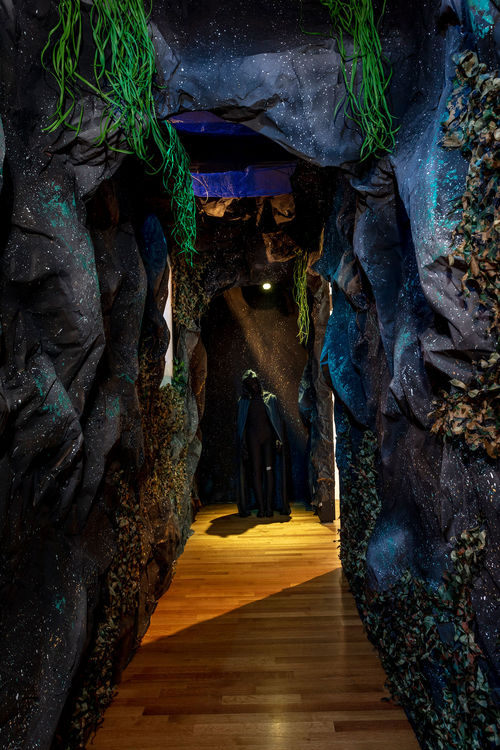 A rock-like hallway in a haunted house, with a hooded figure at the end