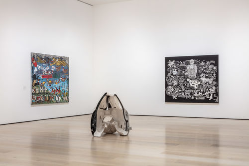 Gallery installation view showing a corner of a gallery painted in white with two paintings on the left and right walls, and a conical sculpture in the foreground