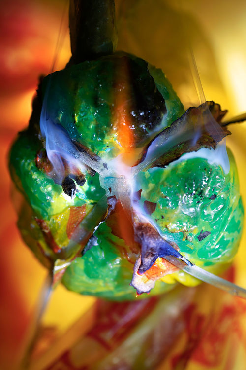 A green blob on fire with blue flames and a yellow background