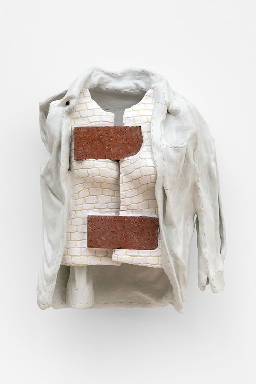 A sculpture of a white vest held together with two bricks
