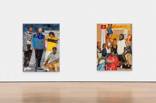 A gallery wall with two colorful paintings of many figures hanging on it