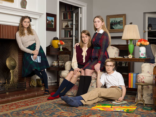 A family portrait of four preteens, arranged in a living room