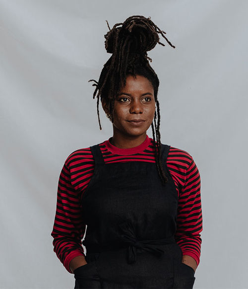 A portrait of a woman in a red striped shirt and black overalls