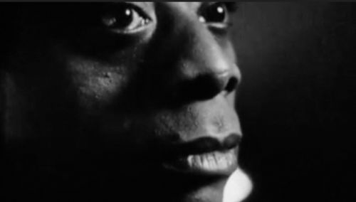 A close crop, black and white portrait of James Baldwin's face. The image frames the top of Baldwin's eyes and extends down to the middle of his chin. It is a sideways glance although Baldwin does not look directly at the camera but away to an undisclosed beyond.