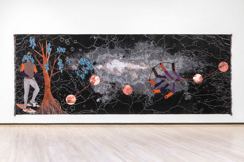 A long black tapestry with a mysterious figure and tree to the left while orbs float in the middle