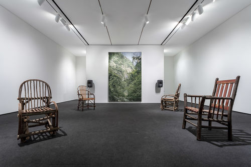 Four wooden chairs sit in the same room as David Hartt's painting