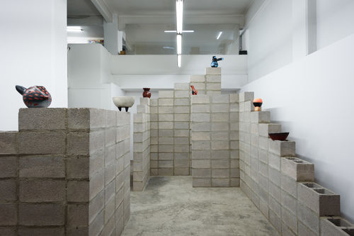 Cinder blocks arranged architecturally to hold small colorful ceramic artworks