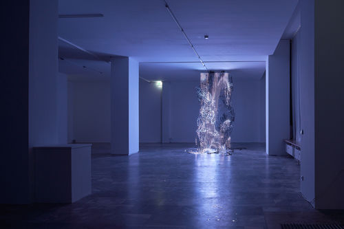 Large sculpture that appears like metallic flowing liquid frozen in time