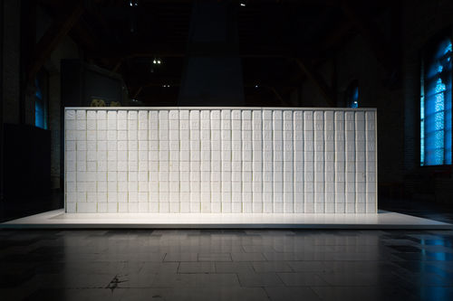 Large wall of white cement blocks, each engraved with a letter from the alphabet