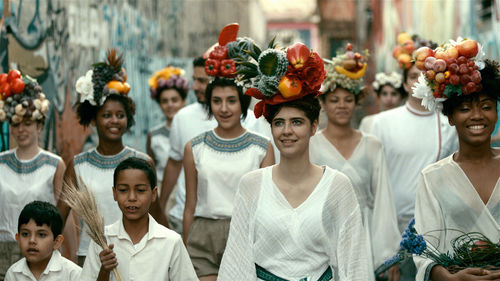 People stand in white robes with flowers on their heads