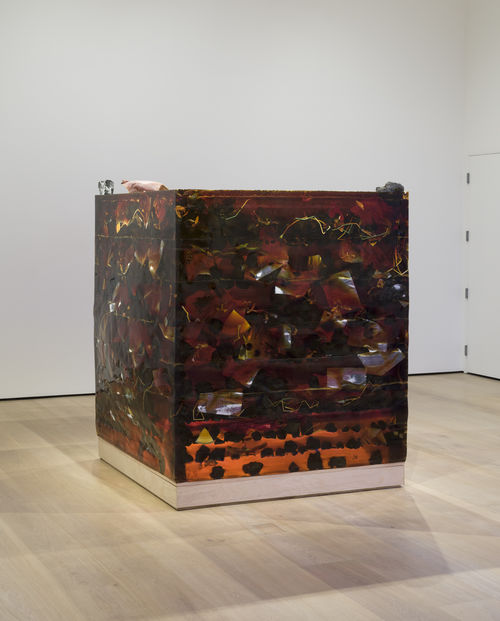 Huge amber block, sitting on a wooden surface, filled with various paper and other debris.