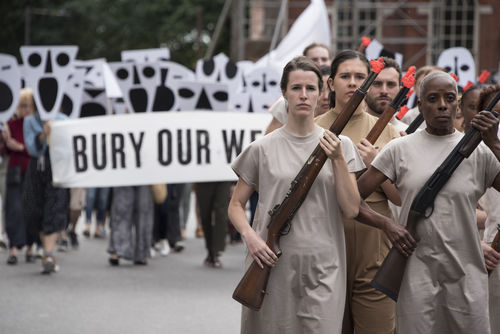 Protest occurs. Women wearing all brown hold old rifles