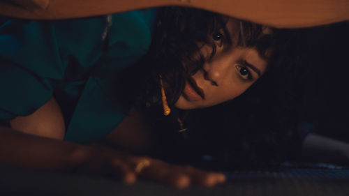 A person lying on the floor, peeking out from under something with an alarmed look