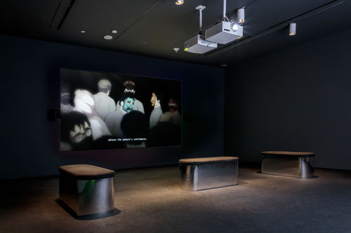 Dark screening room showing video of several anime characters in masks with the caption "Obtain the people's confidence."