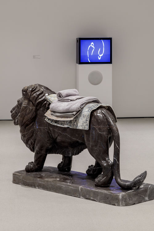 Lion sculpture with textiles laying on top of it.