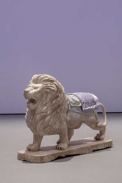 Lion sculpture with textiles laying on top of it.