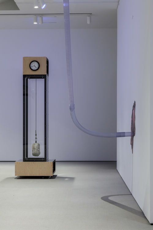 Tall clock sculpture in gallery space.