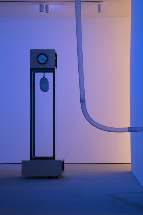 Tall clock sculpture in gallery space.