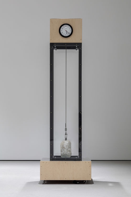 Tall clock sculpture in gallery space.
