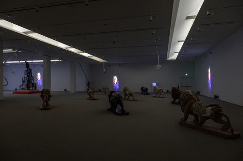 Gallery space with lion sculptures and projections of women in hijabs.