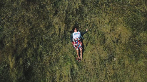 An aerial view of a young woman laying in a field of grass ,wearing a t-shirt that reads "VOTE"