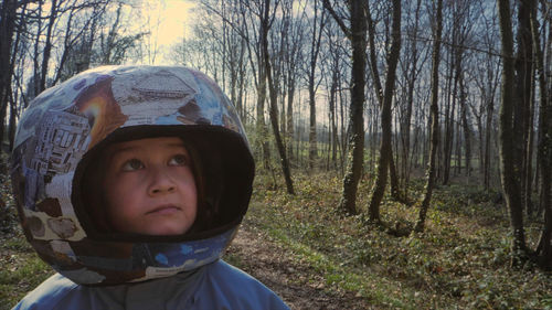 A boy in a helmet stands in a forest.
