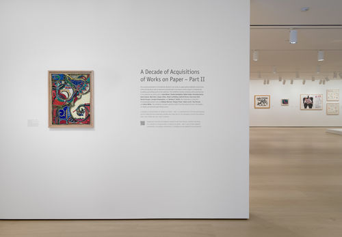 Photo of a gallery wall with a framed painting and exhibition text