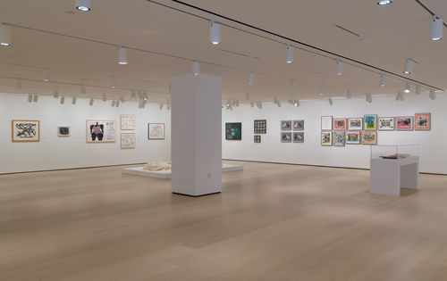 Photo of a wide view of a gallery with many framed works on the wall
