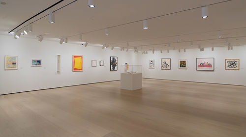 Photo of a wide view of a gallery with many framed works on the wall