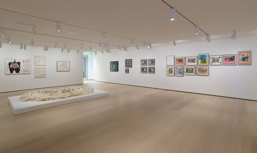 Photo of a wide view of a gallery with many framed works on the wall