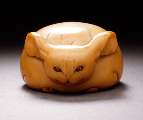 An ivory sculpture of a crouched rabbit, its long ears at its sides