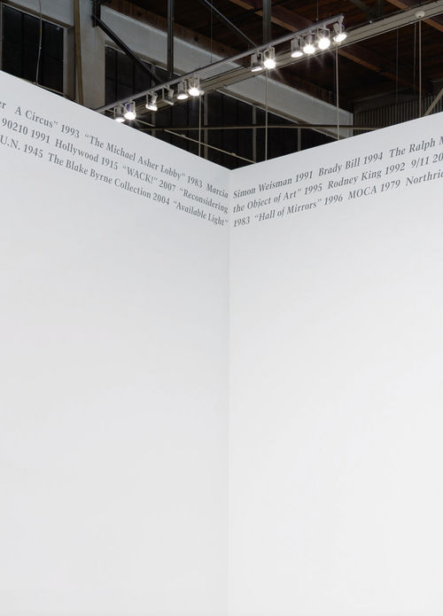 Grey text sits in the top corner meeting of two white walls.