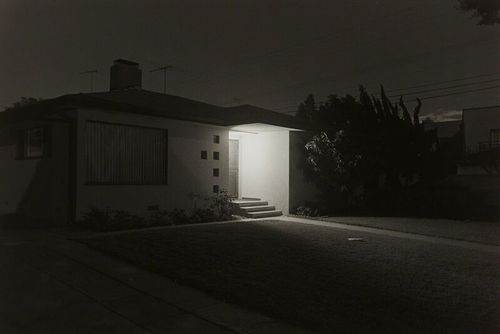 Porch light illuminates a 70s style home at night