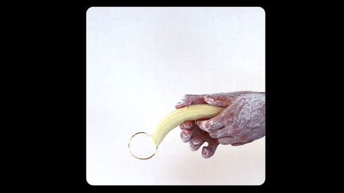 Two hands hold a banana pierced at the tip by a gold hoop