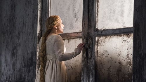 Woman with long hair looks out of foggy window