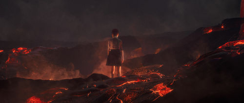 A child in a skirt stands back to the camera in an apocalyptic landscape glowing with lava