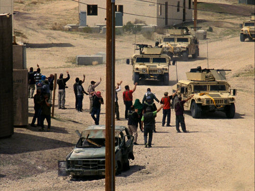 A line of tanks drives down a dirt road