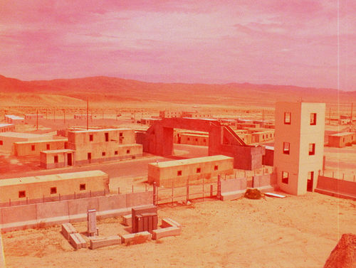 A large, fenced in building in a pink-tinted landscape