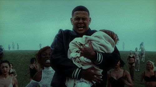 Large man cries while holding baby in a foggy park