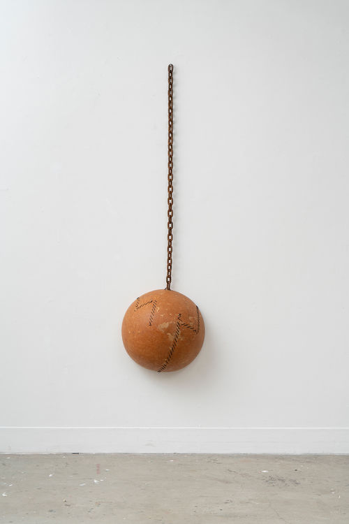 Orange ball hangs on wall on chain link