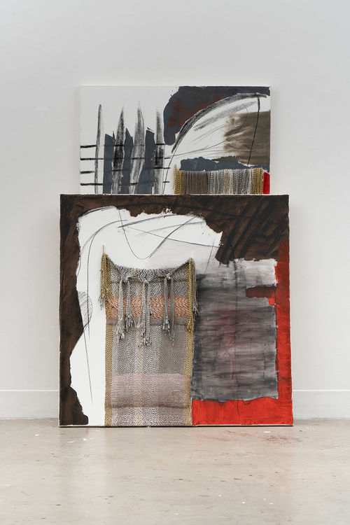 Paintings lean against a wall and against one another